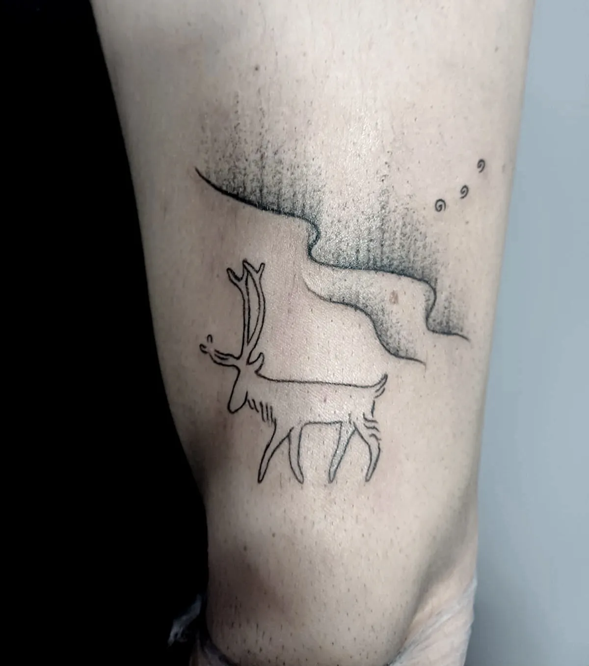 tattaggio fine-line di una renna con aurora boreale